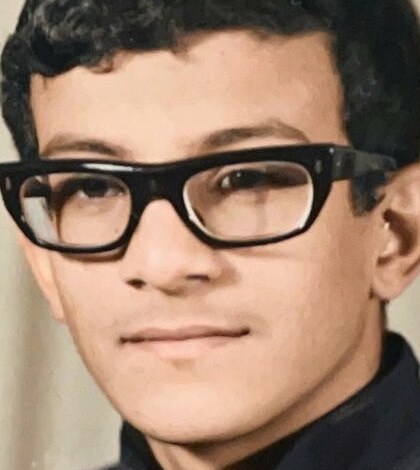 The same face restored and colorized by Colorify, a young man in thick-framed glasses, from an old studio portrait